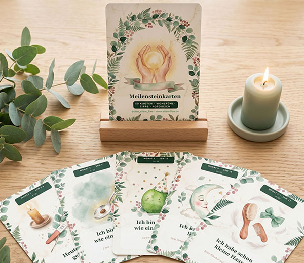 Meilensteinkarten für Babys mit botanischem Aquarell-Design, aufgestellt neben Kerze und Eukalyptus auf einem Holztisch